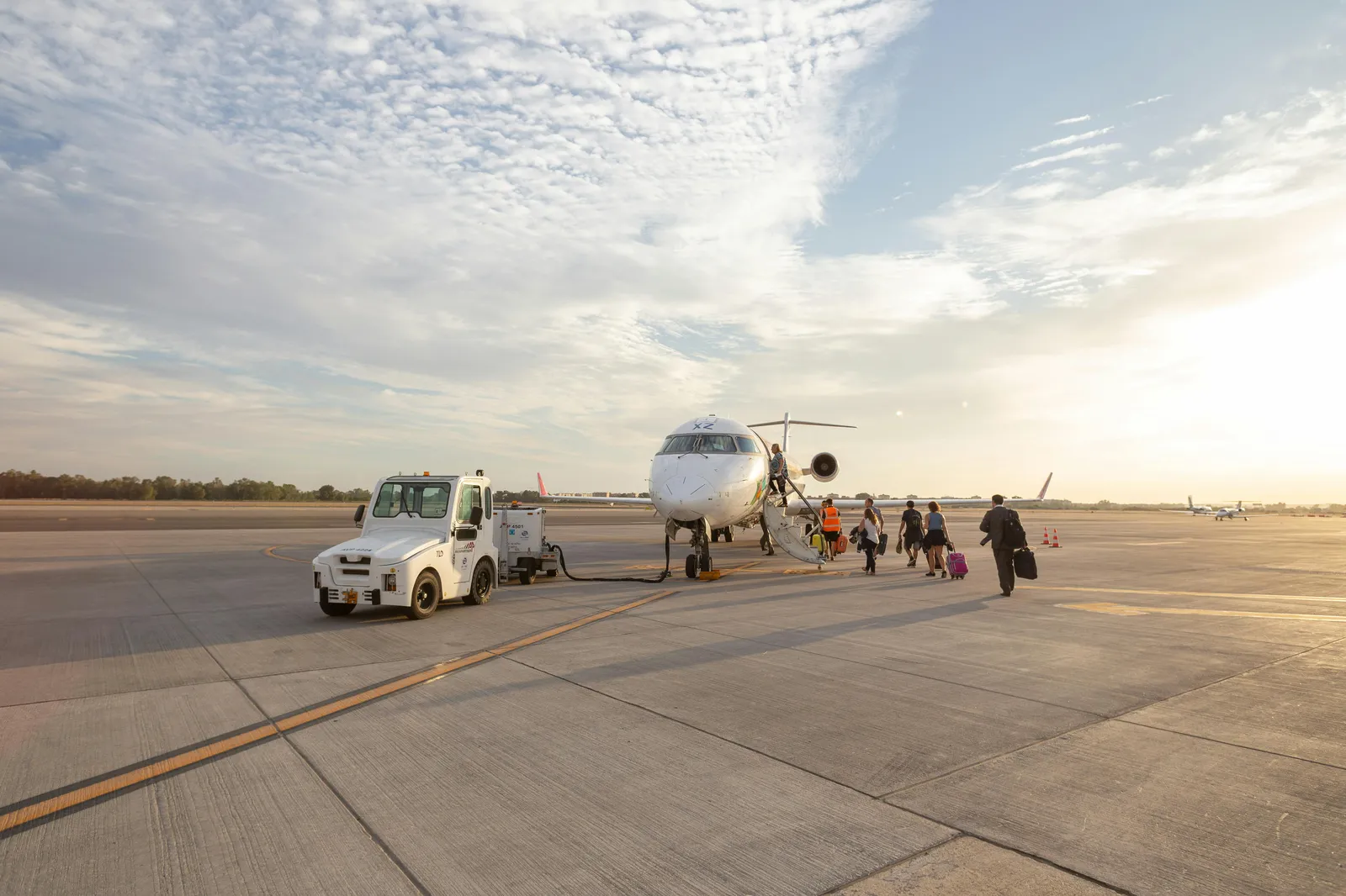 Two people walking toward a small white airplane on the ramp.