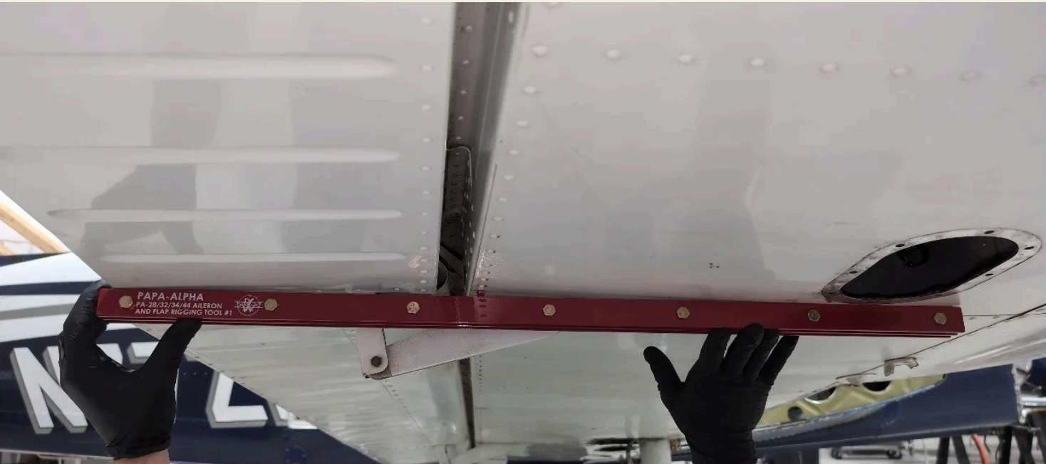 The flap-and-aileron rigging tool establishes three points of contact: two on the wing and one at the flap's trailing edge.